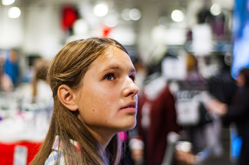 Teenage girl shopping for clothes inside Clothing store at shopping center