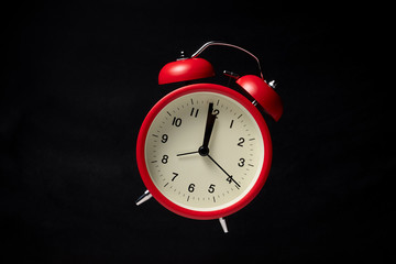 Red vintage alarm clock floating in the dark with blackboard background