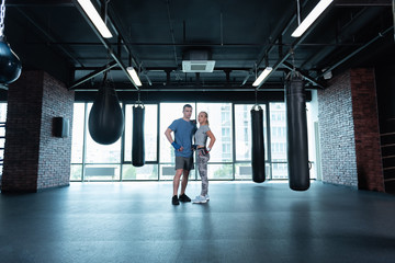 Professional trainers. Two professional fitness trainers standing in spacious gym near big window with city view