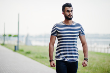 Handsome tall arabian beard man model at stripped shirt posed outdoor. Fashionable arab guy.
