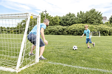 Man with child playing football outside on field