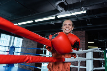 Free time. Beaming athletic woman training in boxing ring while having free time from work