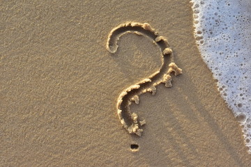Fototapeta na wymiar A question mark drawn on the sand of a beach. Who is there ? What do I need?