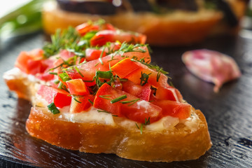 Bruschetta with fresh tomatoes and cheese on a black background. Close-up