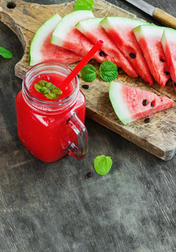 Watermelon juice and pieces of watermelon on a dark wooden background, rustic style