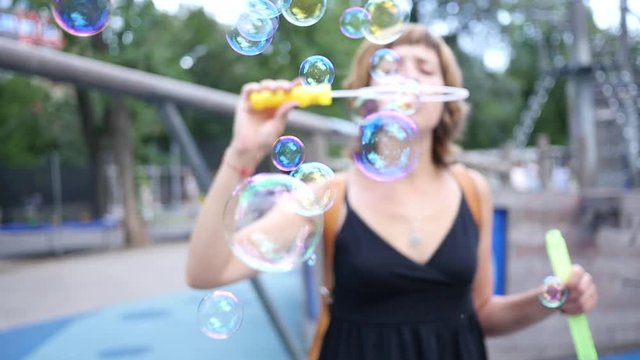 Blowing soap bubbles in slow motion young woman mother have fun in a park