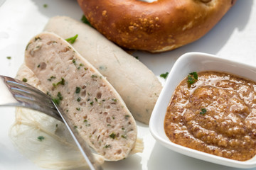 Frau isst Münchener Weißwurst mit Messer und Gabel, süßen Senf und Brezel und löst Wurst richtig aus Pelle