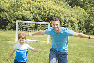 Man with child playing football outside on field