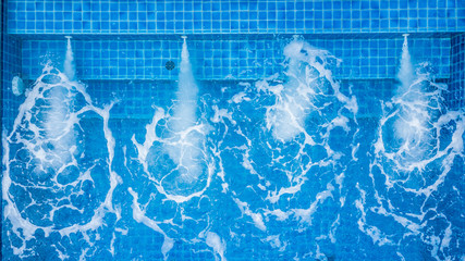 Aerial top view water ripples on blue tiled swimming pool background with jet spa,  View from above...