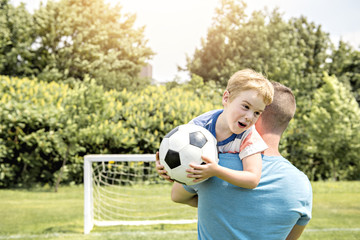 Man with child playing football outside on field