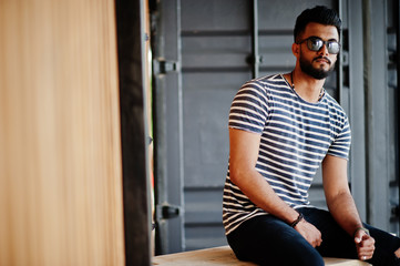 Handsome tall arabian beard man model at stripped shirt posed outdoor. Fashionable arab guy at sunglasses.