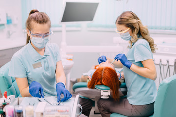 young female assistant preparing tools for dentist doctor during patient treatment