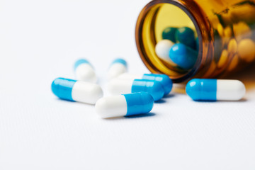 Blue-and-white pills scattered on the table from the bottle.