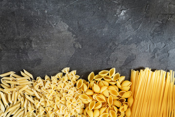 Dry pasta background. Different pasta on dark background. Flat lay. Top view.