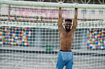 Handsome sexy african american muscular bare torso man at jeans overalls posed at green grass...