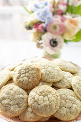 Lavender shortbread cookies in a pile with a bouquet of flowers in the background.