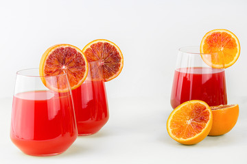 Red orange juice in a glass and oranges. Isolated on white background