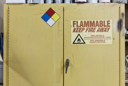 Safety sign reminders mounted to a metal cabinet in a woodworking factory.