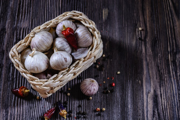 Garlic and small chilli pepper in a wicker basket on a wooden table