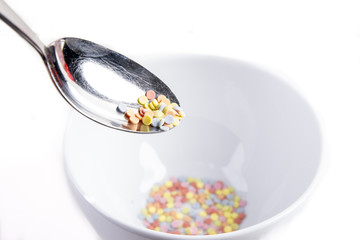 colorful sweet sugar pieces on a spoon over a white cereal bowl