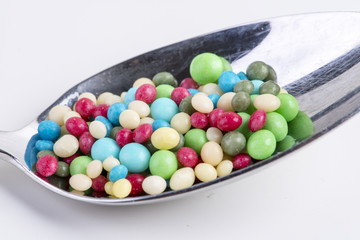 small colorful round pieces of sugar to decorate a cake on a spoon as macro