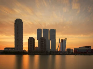 Foto op Plexiglas Erasmusbrug Prachtige zonsondergang achter de skyline van Rotterdam. Foto genomen vanuit de haven met een lange sluitertijd.