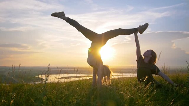 Two young women warming up on the hill at summer sunset