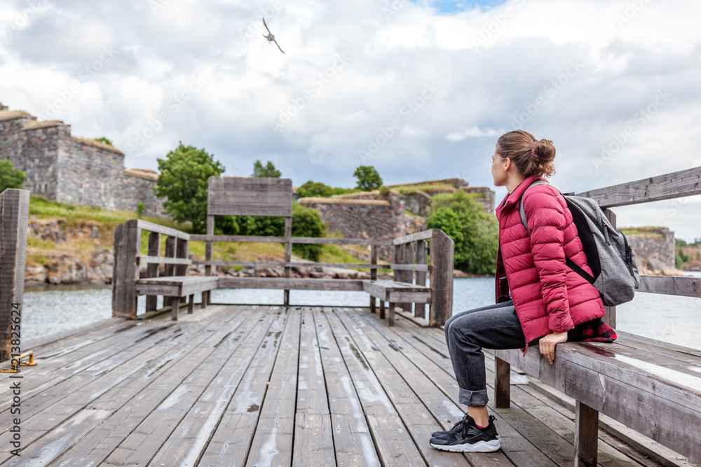 Wall mural Beautiful young woman tourist on a wooden pier on the island of Suomenlinna, travel to Northern Europe, Finland