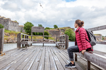 Fototapeta na wymiar Beautiful young woman tourist on a wooden pier on the island of Suomenlinna, travel to Northern Europe, Finland
