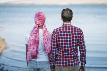 Man and woman with a pink scarf in her head looking a lake