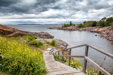 Fototapeta na wymiar Wooden paths stairs along the coast on the island of Suomenlinna, a beautiful seascape. Islands of Finland