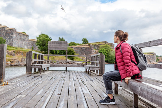 Beautiful young woman tourist on a wooden pier on the island of Suomenlinna, travel to Northern Europe, Finland