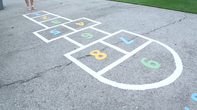 little girl having fun playing hopscotch