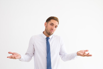 Doubtful business man shrugging shoulders and throwing up hands. Attractive guy looking at camera....