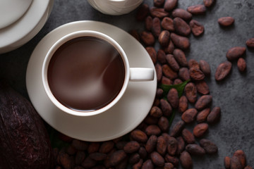 Hot chocolate and Cocoa pod cut exposing cocoa seeds on dark table, top view with copy space