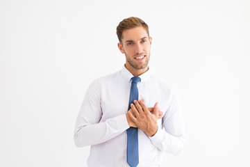 Thankful business man keeping hands on chest and looking at camera. Attractive guy thanking somebody. Gratitude concept. Isolated front view on white background.