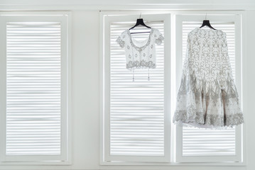 Wedding dress saree and blouse of indian bride hanging on the white wall windows