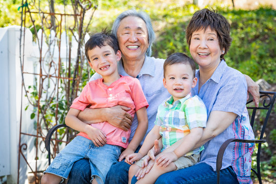 Chinese Grandparents and Mixed Race Children Sit on Bench Outdoors
