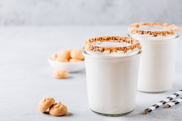 Vanilla milkshake with crispy cookies in glass mason jar on gray background