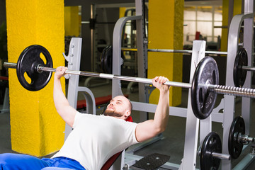 Sport, fitness, training and people concept - Muscular man doing heavy exercise pumping up muscles on bench press