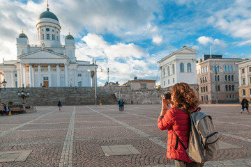 A beautiful young woman traveler with a camera on Senate Square in Helsinki, the capital of...
