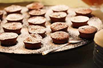 Dolci mono dose al cioccolato disposti su un vassoio con spolverata di cacao sopra