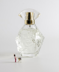 miniature figure women with shopping cart standing in front of perfume bottle
