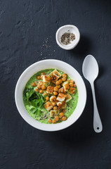 Broccoli soup with spicy chickpeas and croutons on a dark background, top view. Vegetarian healthy food concept