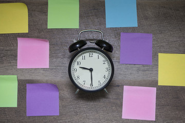 Black bell clock background is wooden and filled with blank color notes