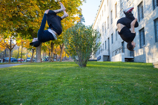 Two young men doing a side flip or somersault while they practicing parkour on the street. 