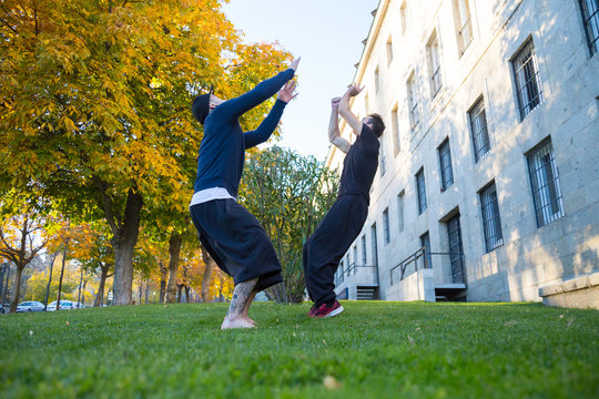 Two young men doing a side flip or somersault while they practicing parkour on the street. 