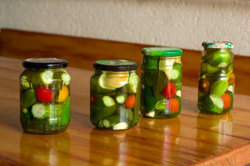 canned tomatoes and cucumbers in a jar on a wooden table