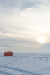 Ice fishing huts on a frozen lake in Ontario at sunset