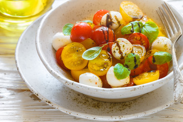 Delicious summer salad of yellow and red cherry tomatoes, mozzarella with Basil, spices and balsamic. Caprese